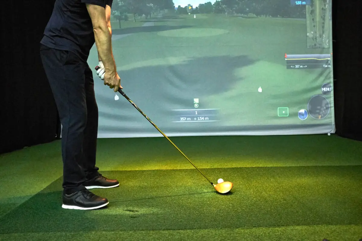 Man hitting golf ball on a simulator