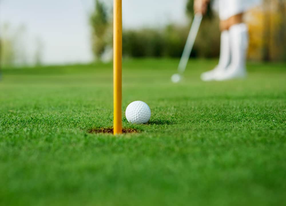 Golfer putting next to the hole